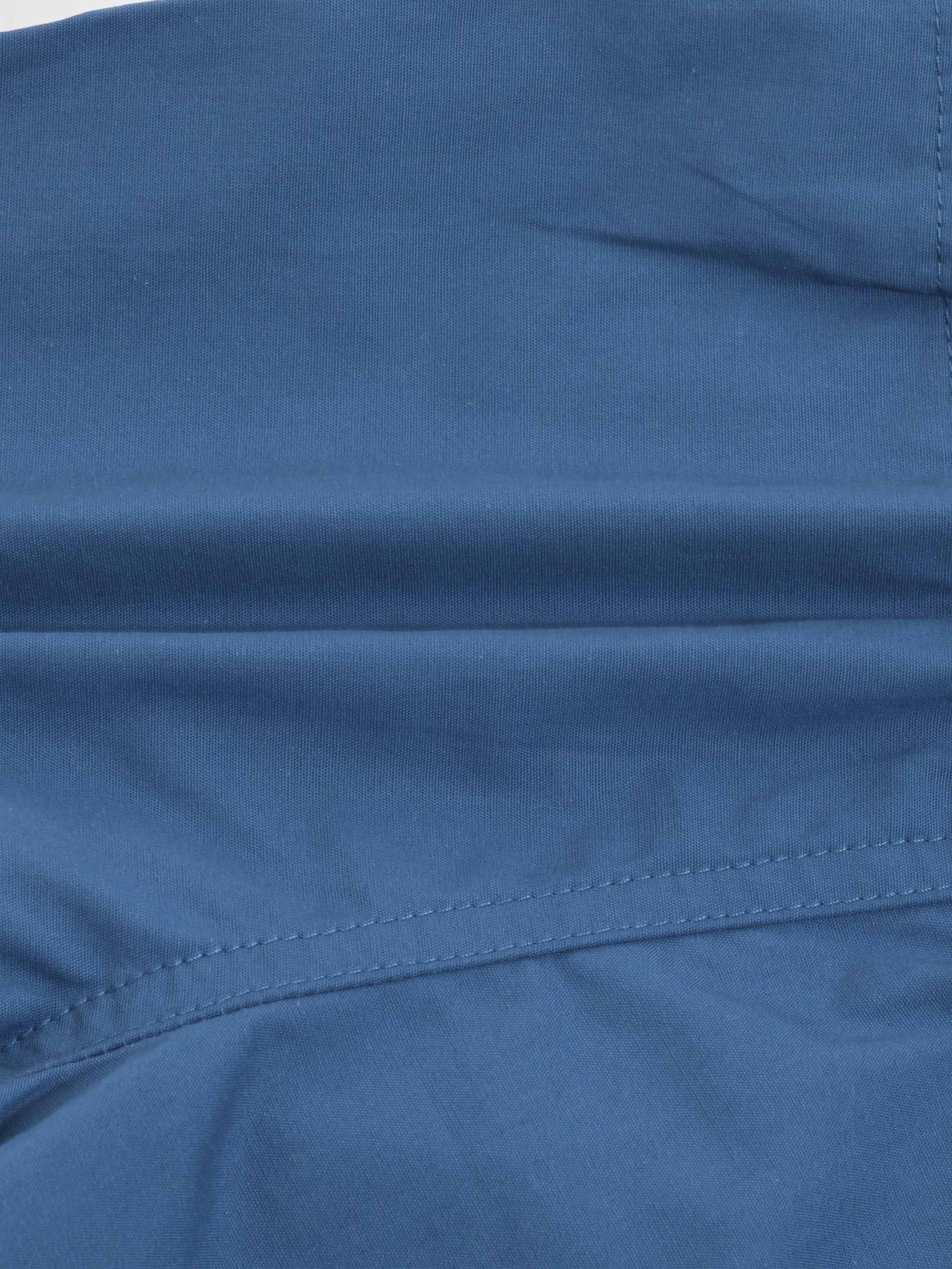 Blue cotton shorts fabric close-up with visible stitching and seam.