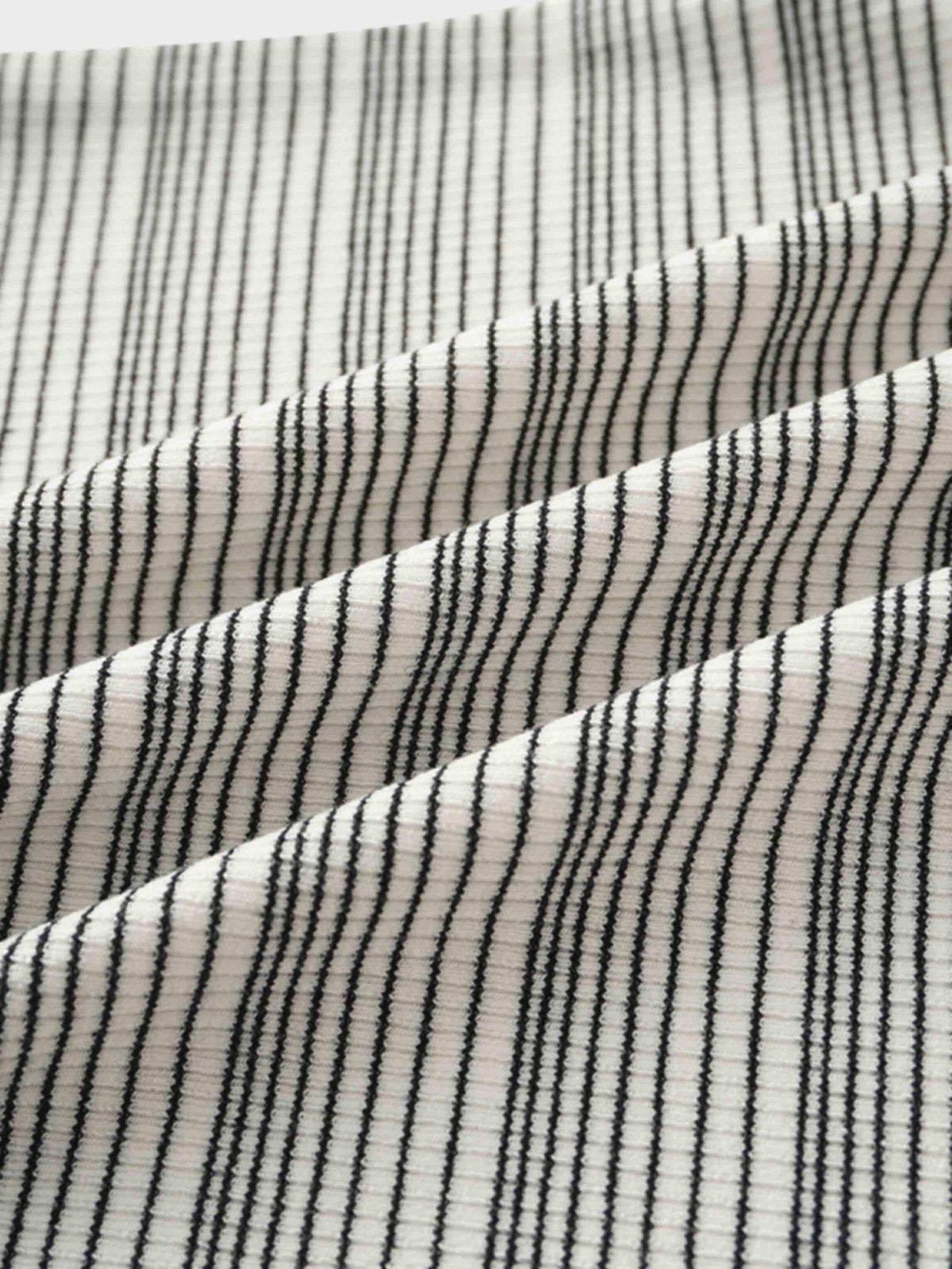Close-up of white textured knit fabric with thin black horizontal stripes.