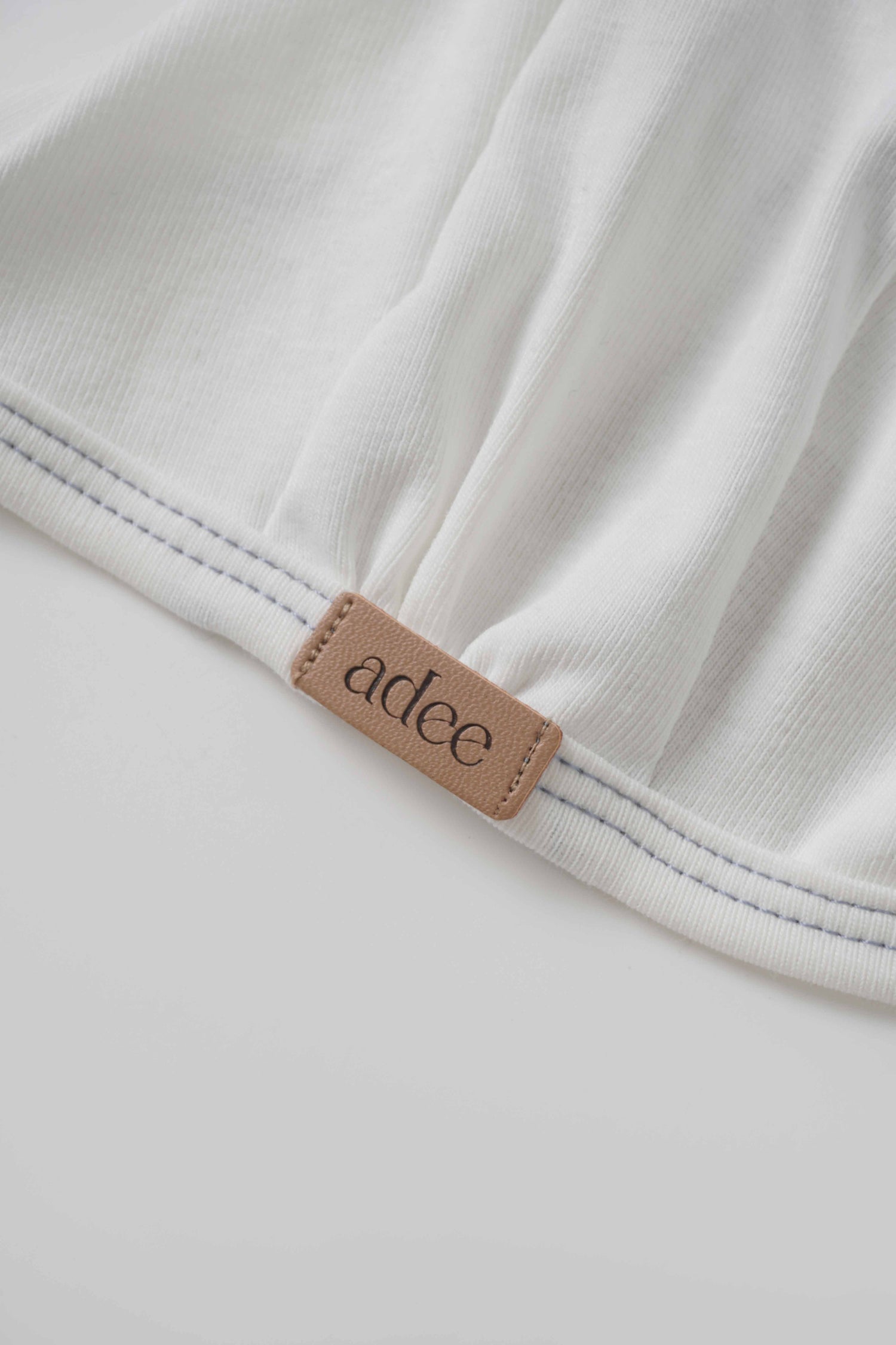 Mini Gallery Bonnet for boys by Adee; white fabric with blue stitching and tan logo patch