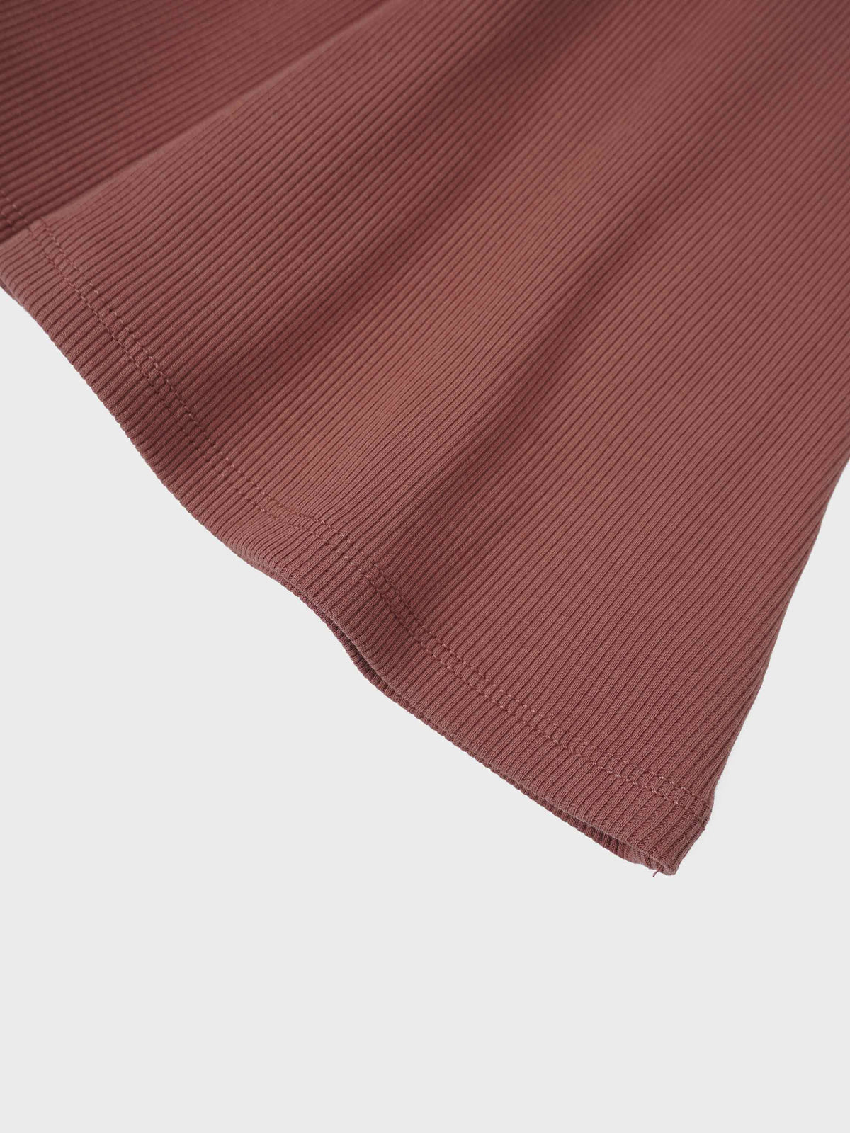 Brick-colored ribbed knit skirt hem close-up.