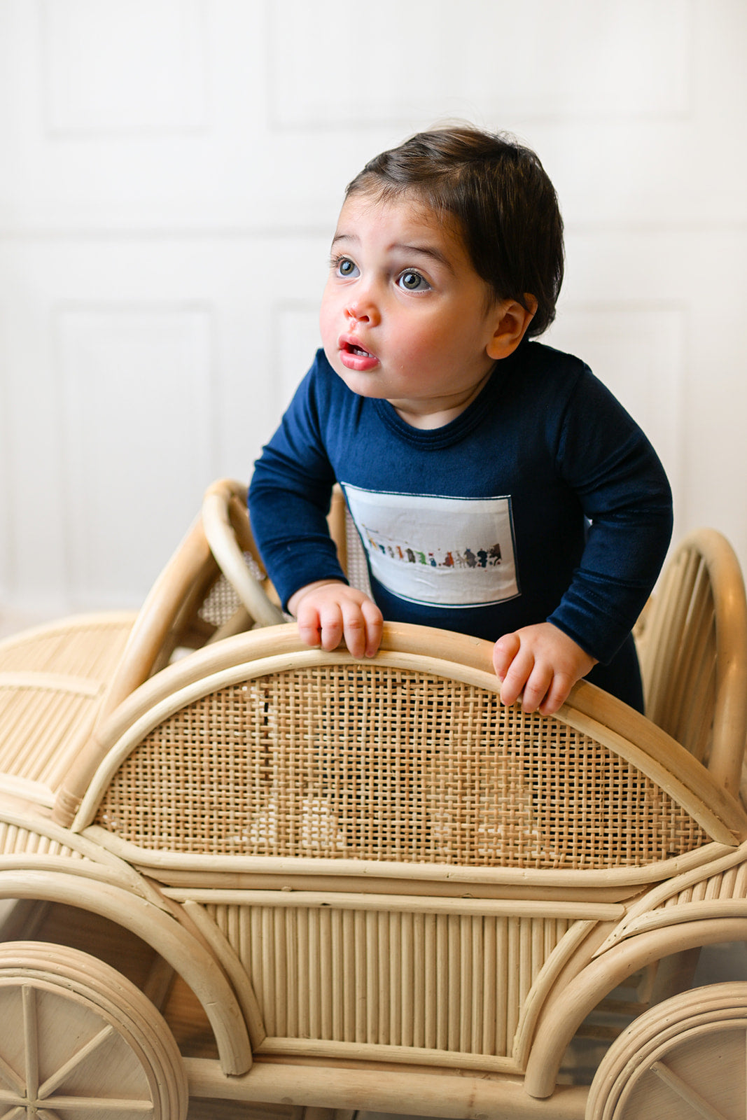 Baby boy in navy outfit leaning on a woven wicker toy car, Animal Band Stretchy - Navy.