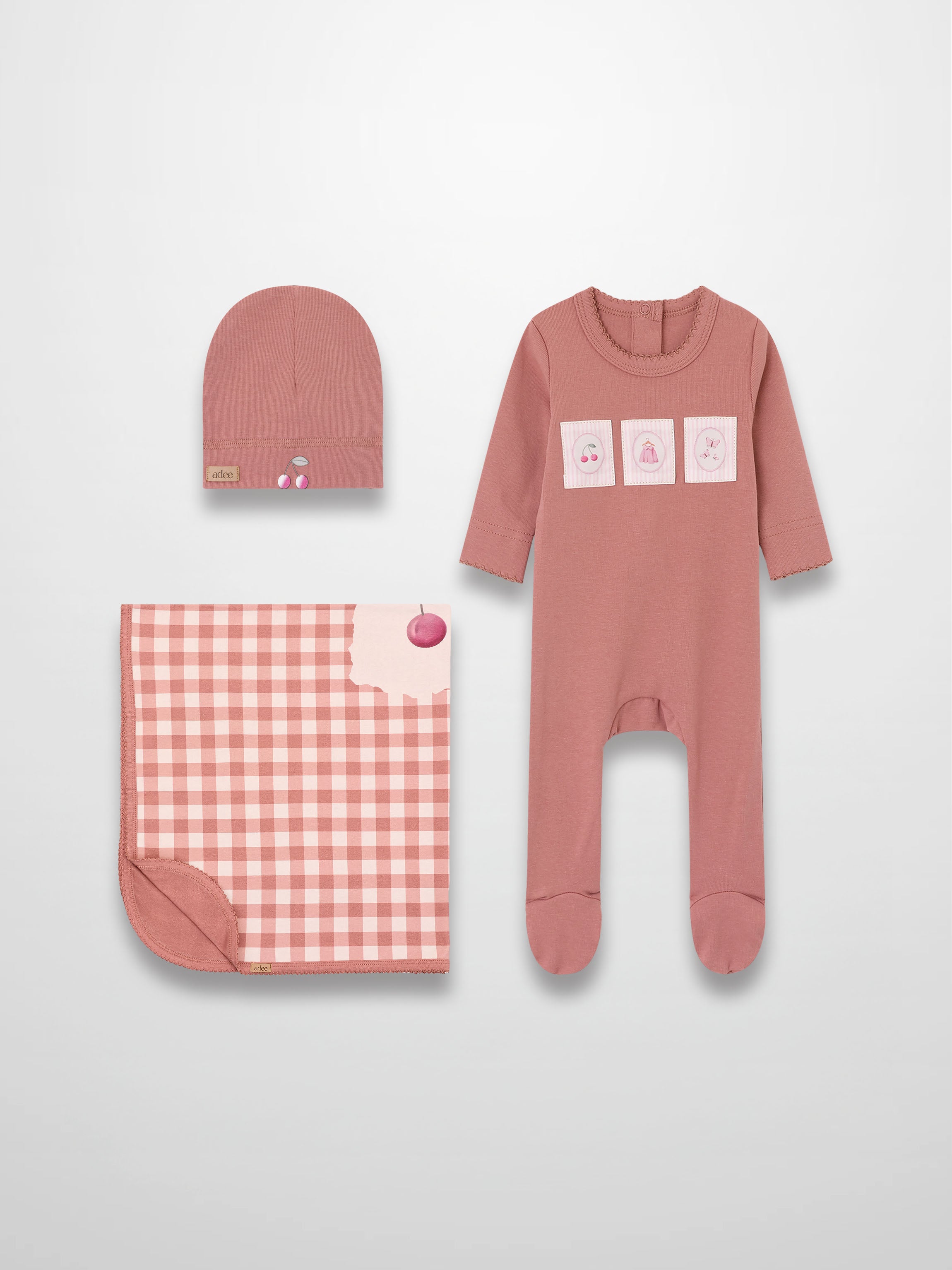 Cherry Frame layette set for girls by Adee in pink, includes a footed onesie, matching hat, and gingham blanket.