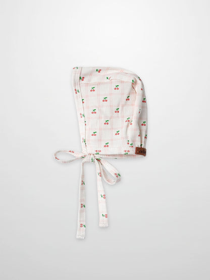 Adee Cherry Window Bonnet for girls, soft thin-ribbed fabric with pink cherry print and tie strings.