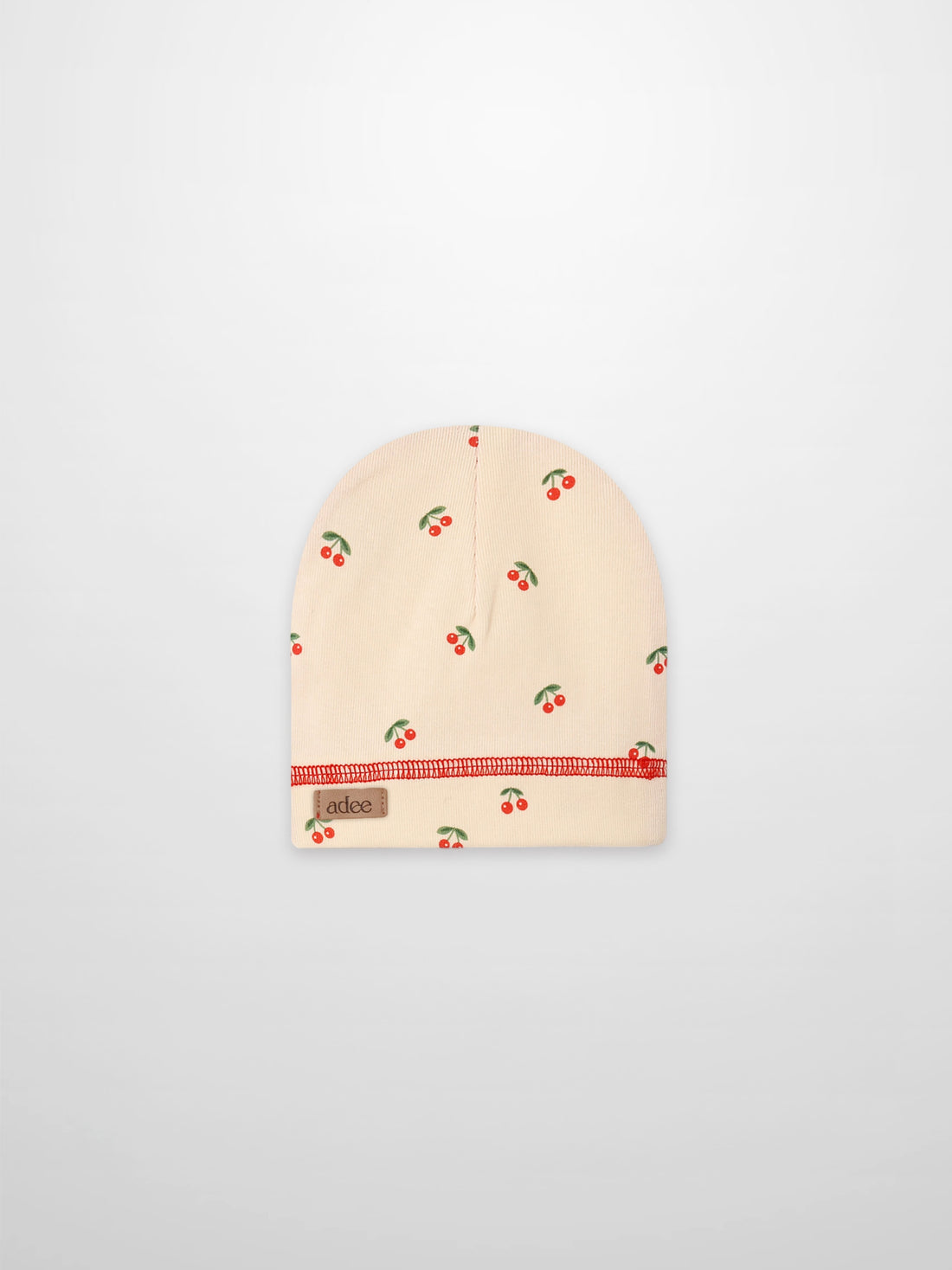 Red Cherry Hat for girls; beige knit beanie by Adee with scattered cherries and red stitching.