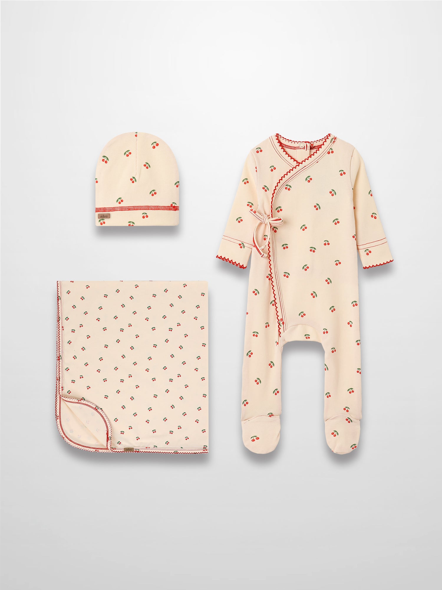 Red Cherry layette set by Adee for girls, cream with red cherries and green leaves; includes hat, blanket, romper.