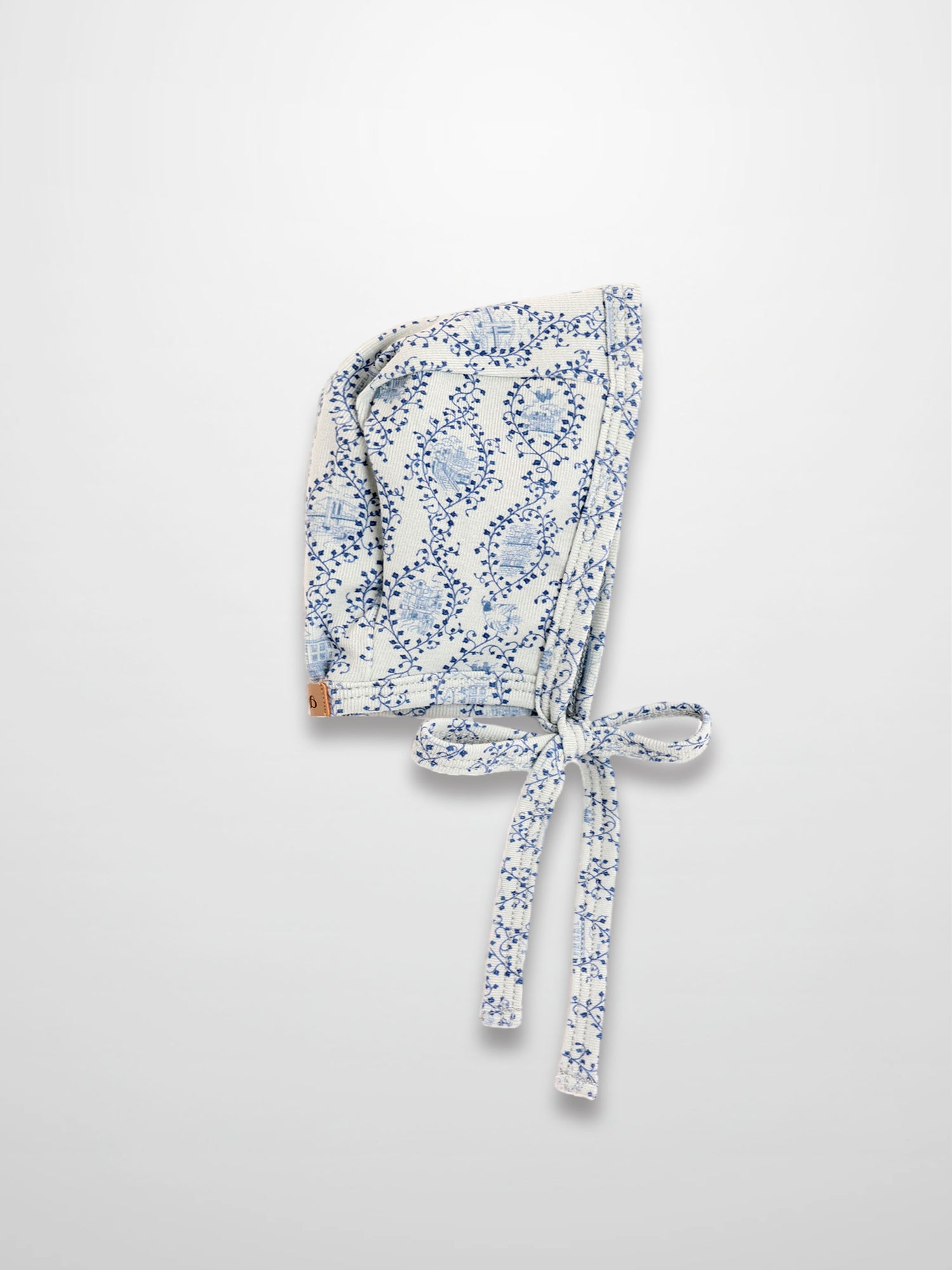Blue Charm Bonnet for boys; white fabric with dark blue vine pattern and tied strings, Adee