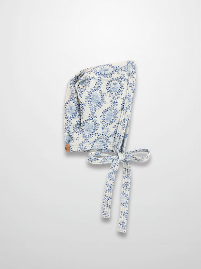 Blue Charm Bonnet for boys; white fabric with dark blue vine pattern and tied strings, Adee