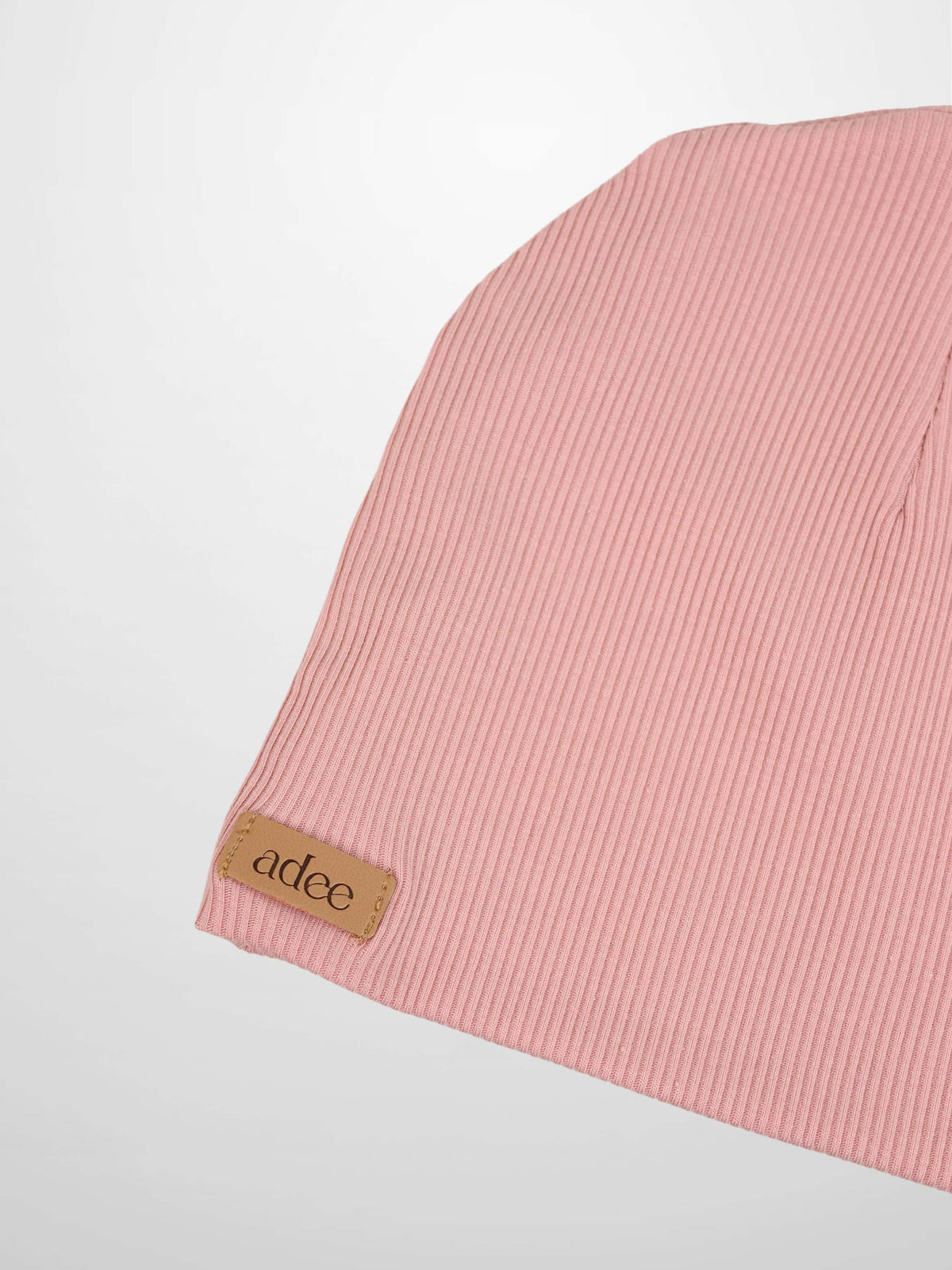 Thin ribbed girls beanie in light pink with a tan Adee logo patch.