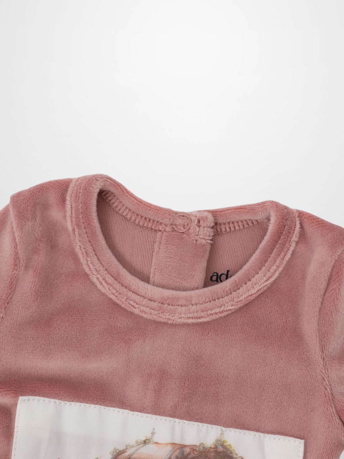 Light pink velour baby footie with a carriage embroidered on a fabric patch.