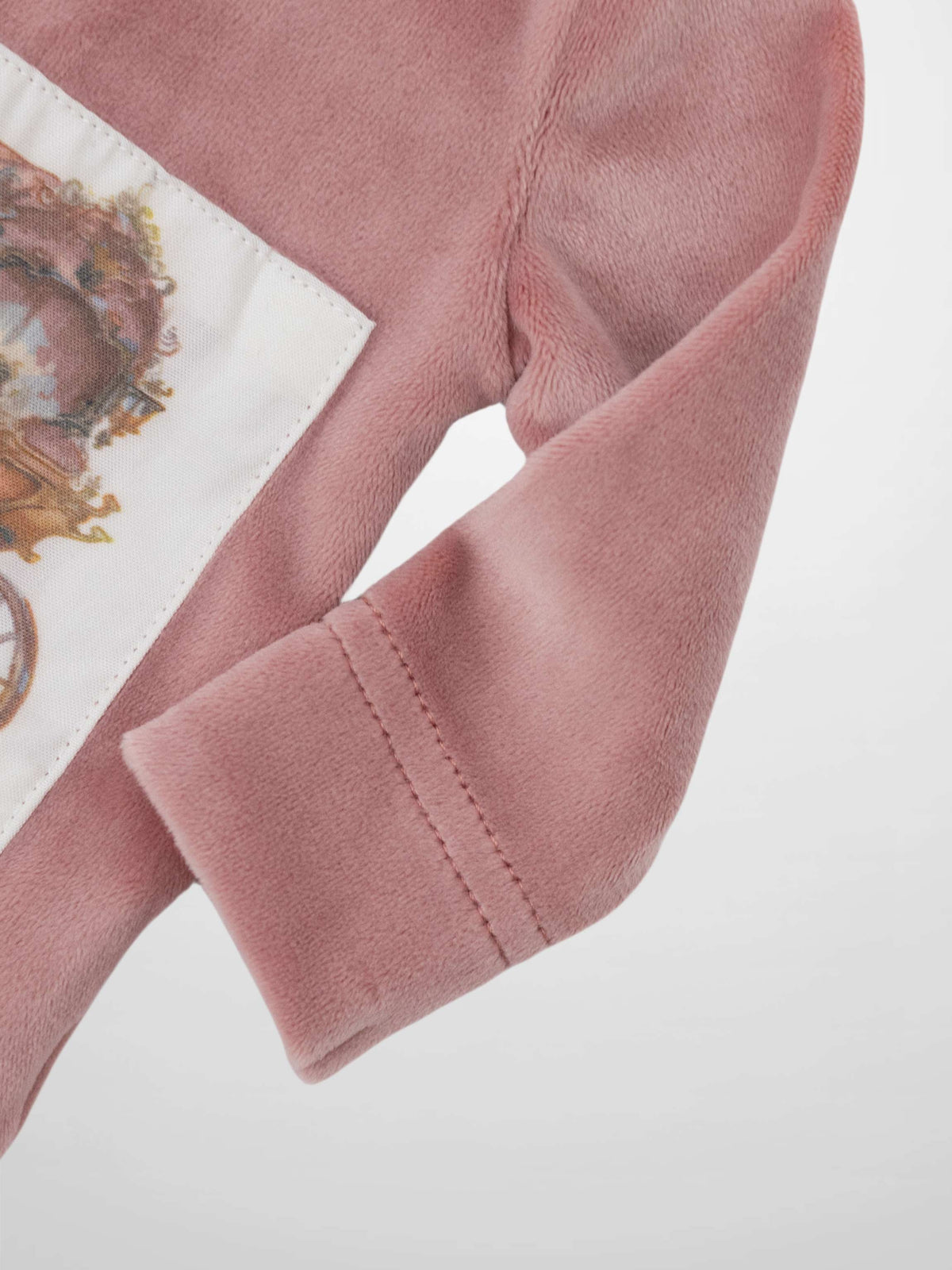 Pink velour fabric with a white patch embroidered with a vintage carriage.