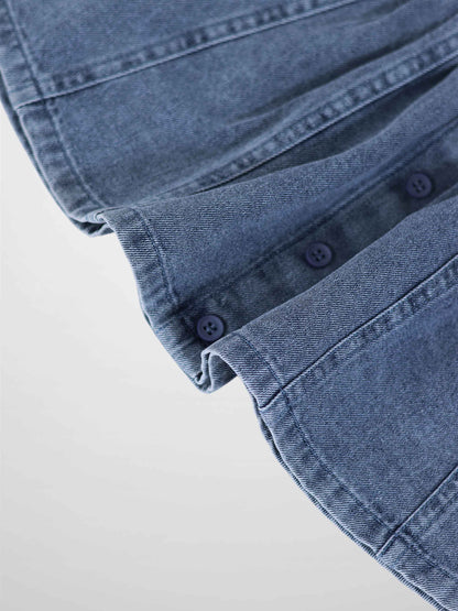 Paneled blue denim fabric close-up with seam lines and blue buttons.