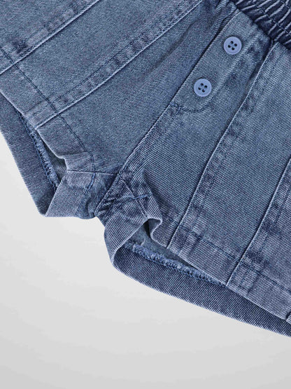 Paneled blue denim shorts with button front detail and rolled hem, close-up