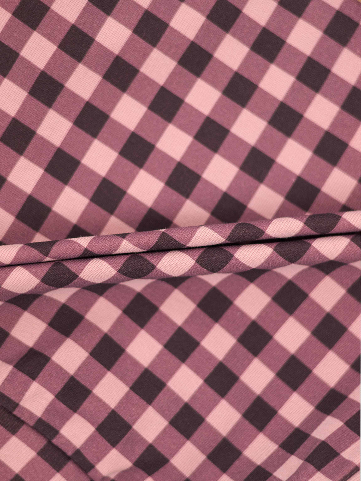 Close-up of pink and red gingham stretchy fabric for a baby girl footie.