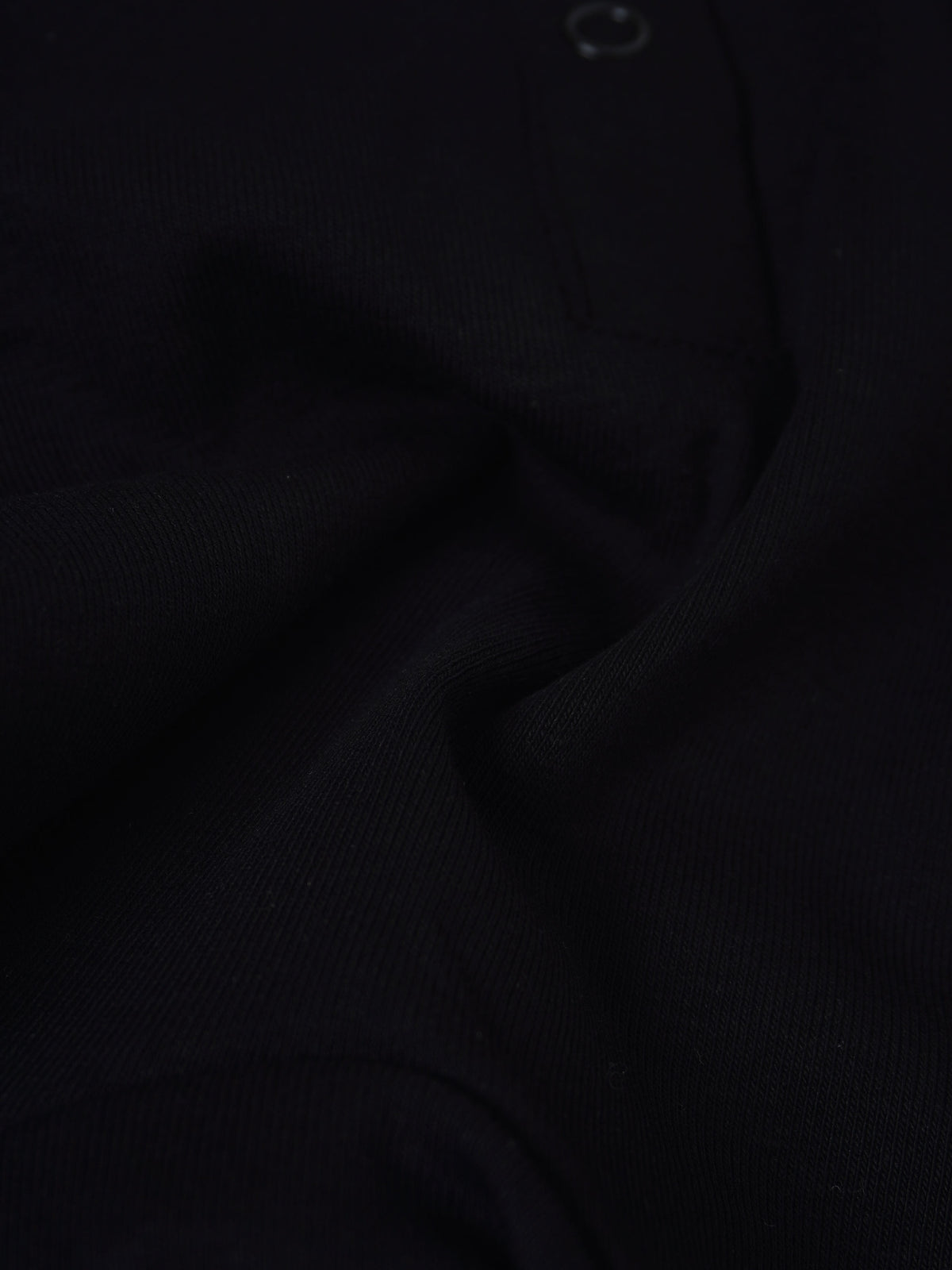 City Stretchy - Black unisex jumpsuit footie fabric close-up showing textured knit material with no visible logo