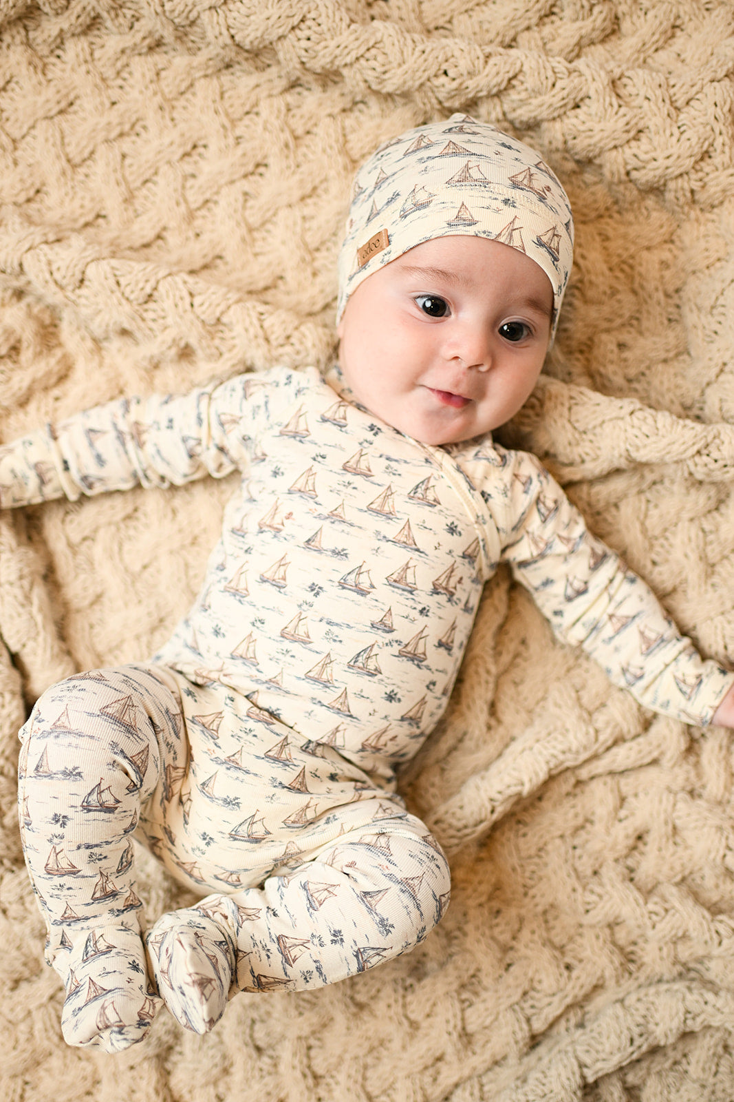 Cute baby boy wearing a Adee baby jumpsuit and a beanie hat with sailboat print