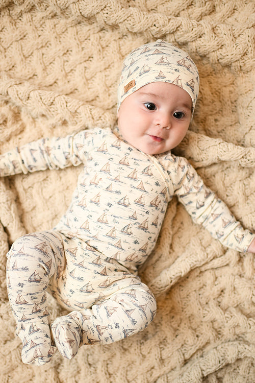 Cute baby boy wearing a Adee baby jumpsuit and a beanie hat with sailboat print