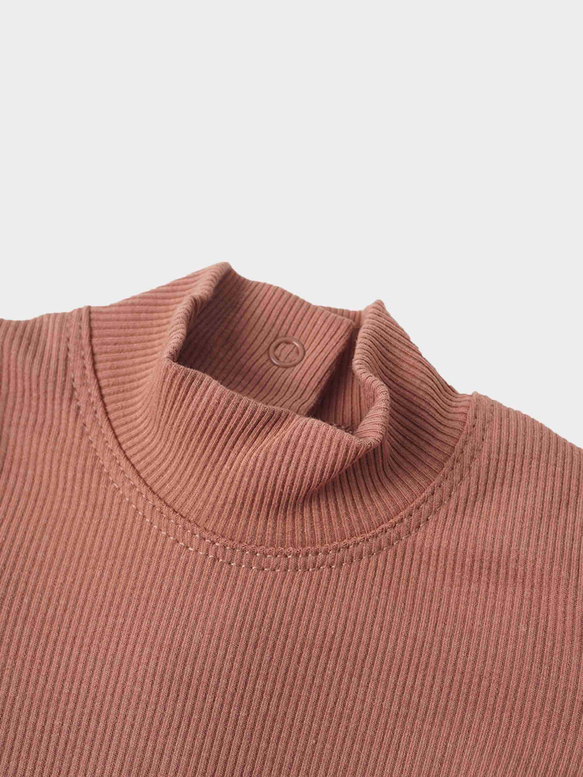 Pink ribbed mock neck detail on a stretchy baby garment with back snap closure.