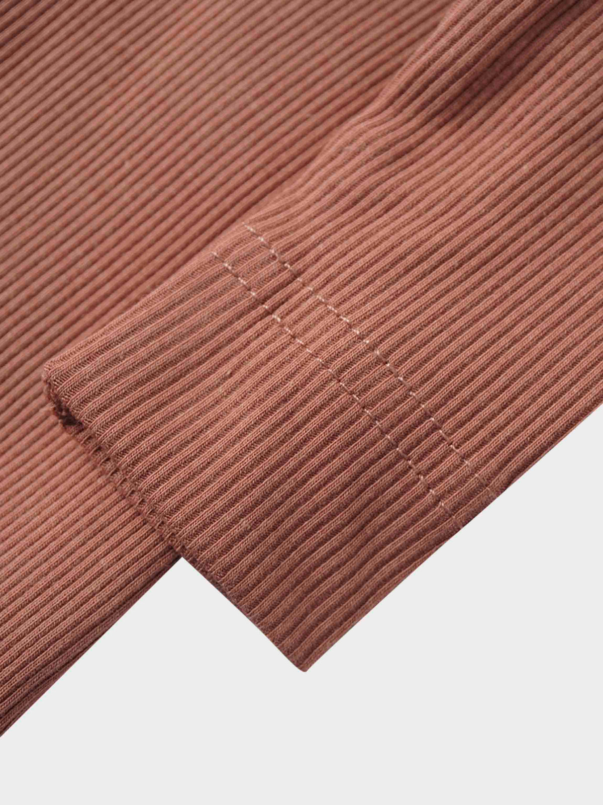 Pink thin ribbed knit fabric with a stitched cuff, close-up of a baby footie detail.
