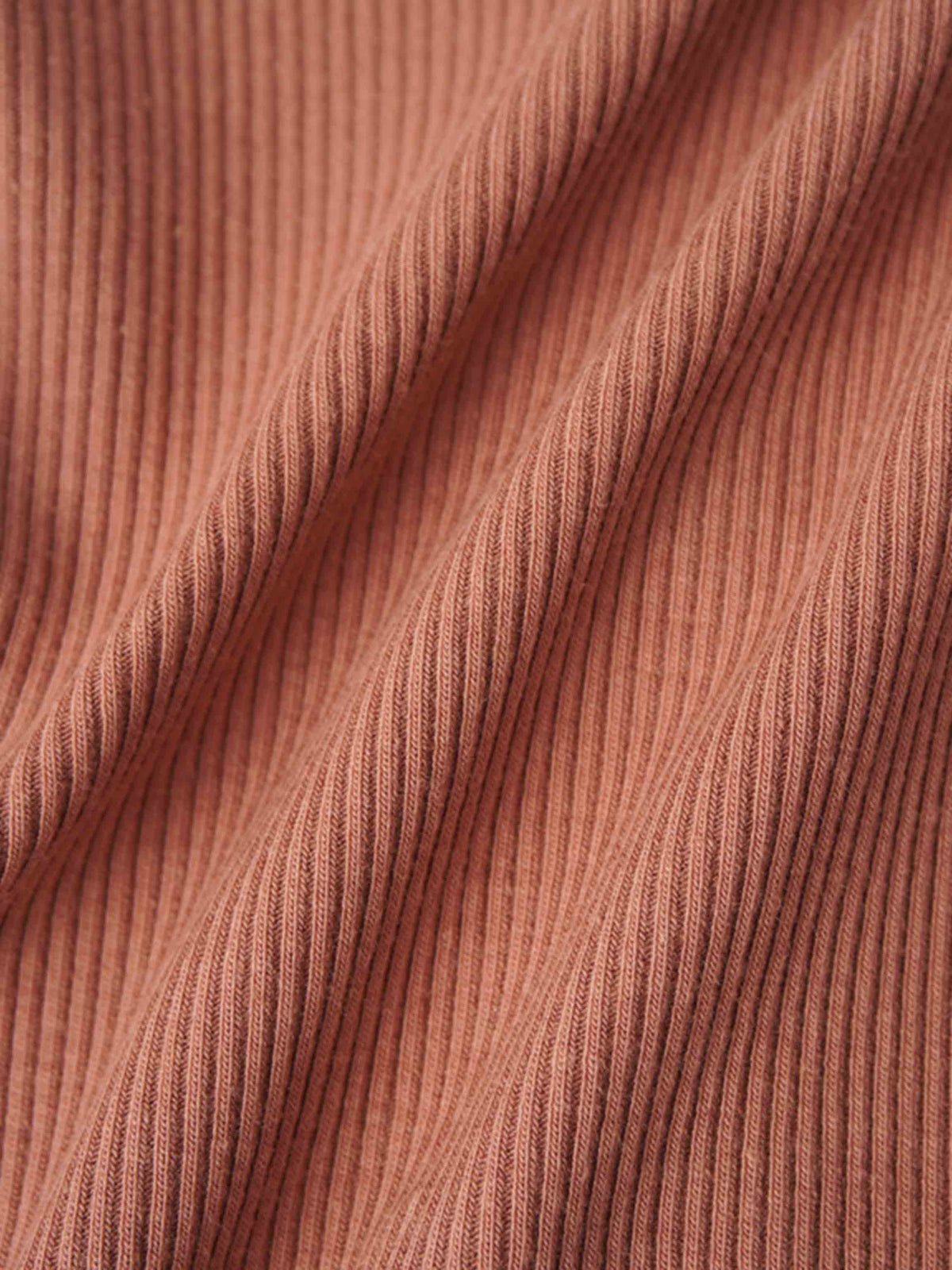 Close-up of pink ribbed knit fabric for a baby footie with a mock neck