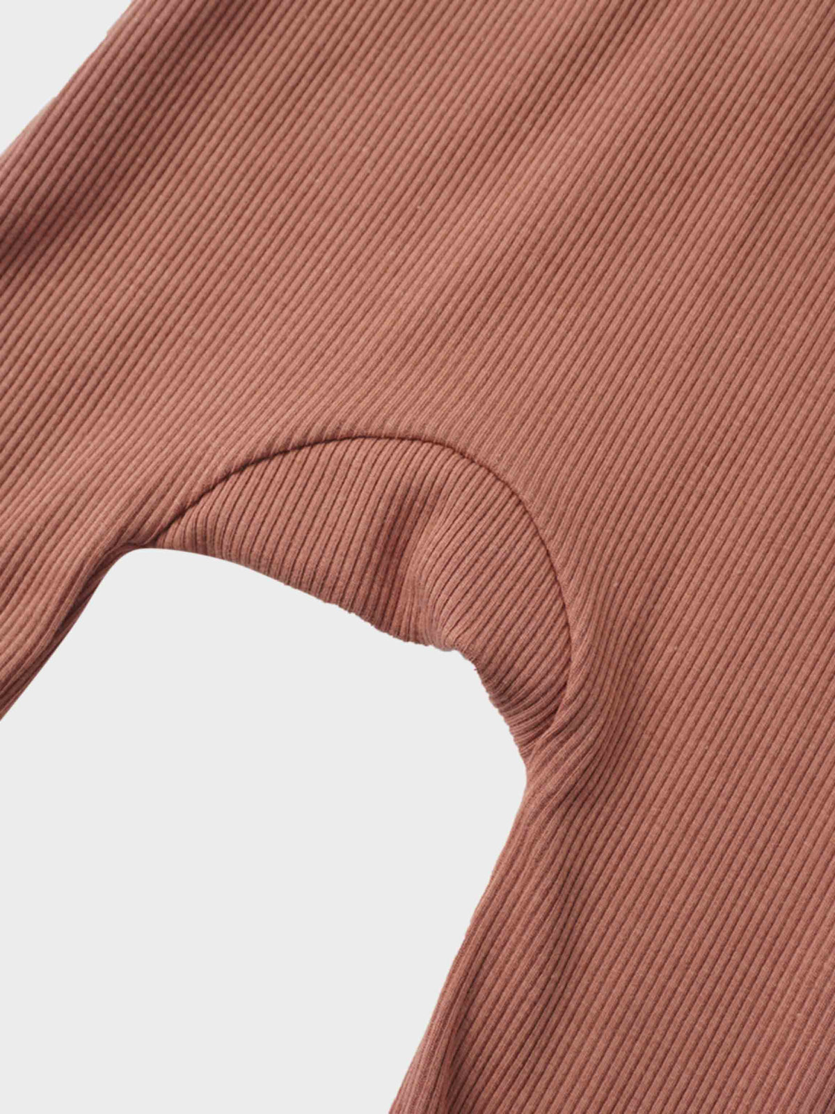 Pink ribbed knit fabric close-up showing a curved armhole seam on a stretchy garment.