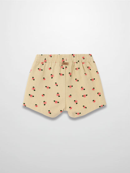 Tan floral shorts with pink blossoms and green leaves, elastic waistband, curved hems.