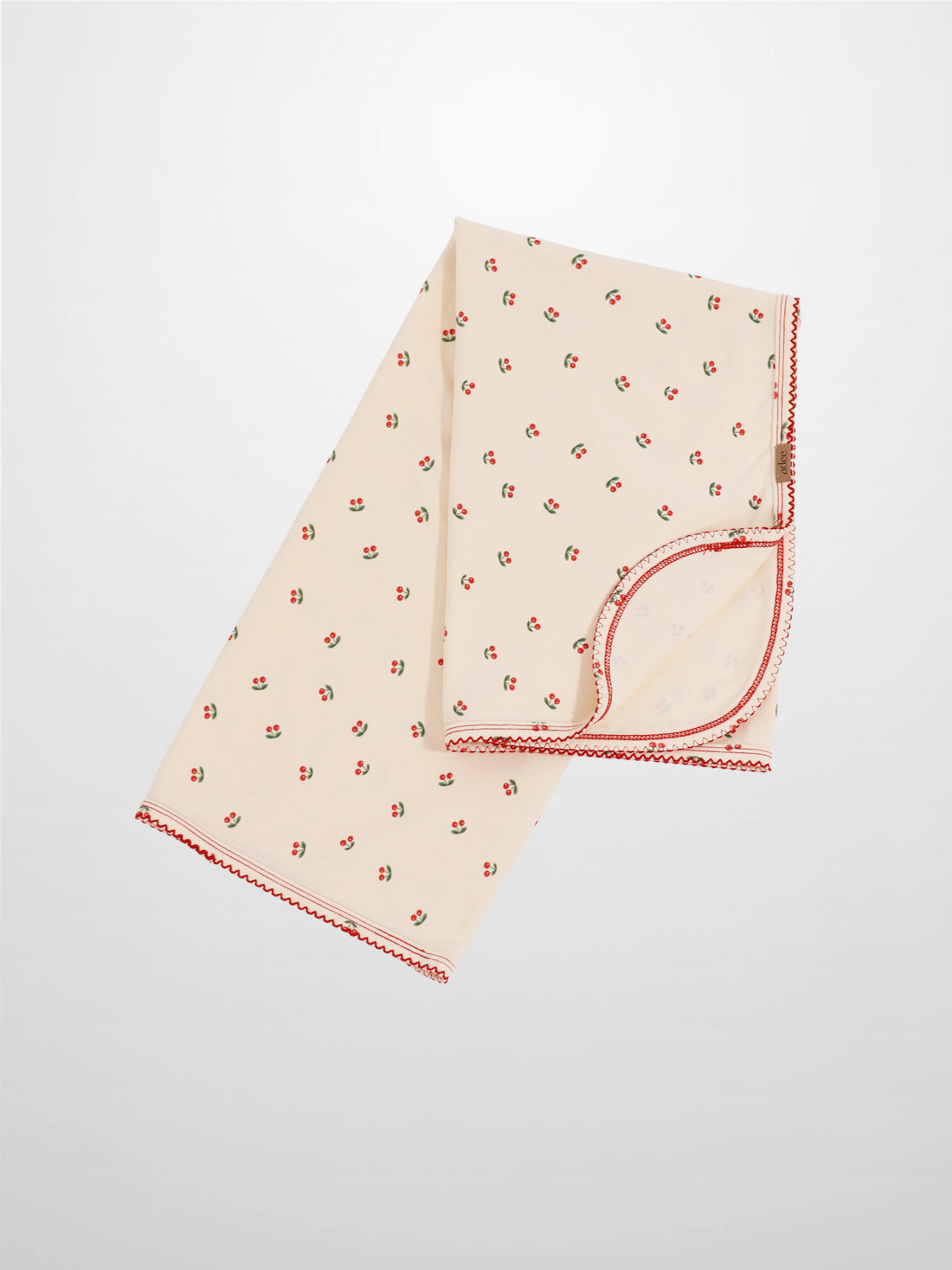 Red Cherry Blanket with Lace by Adee, pale pink receiving blanket with scattered red cherries and red lace trim.