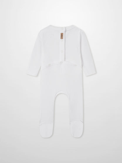 Legacy Stitch Stretchy white unisex romper by Adee with ribbed knit and back snap placket; brand tag visible.
