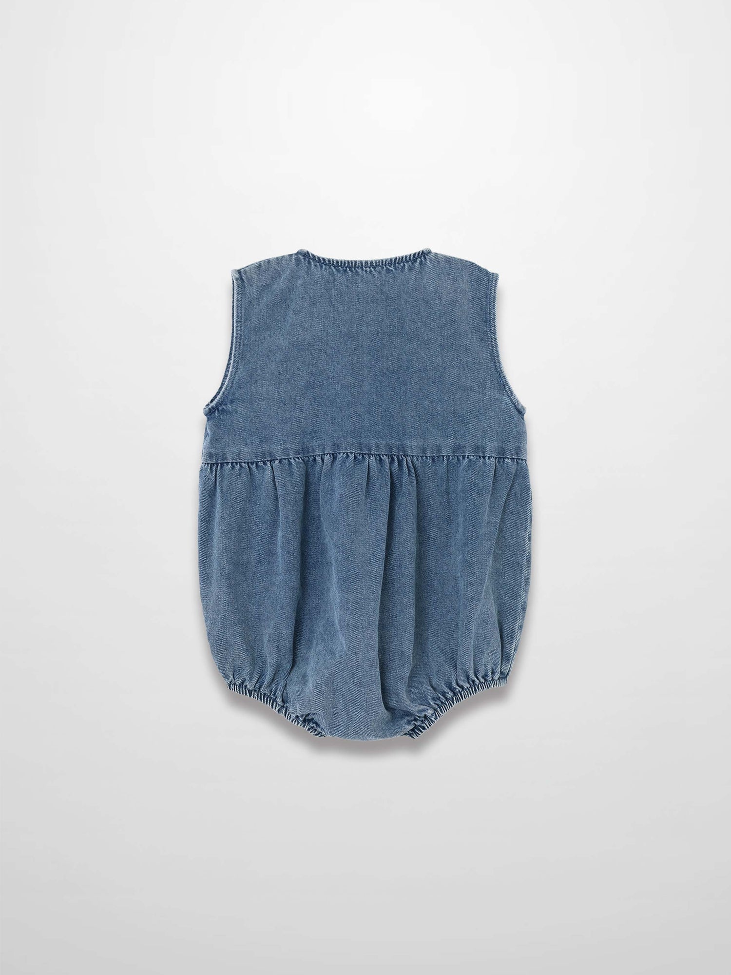 Back view of blue denim romper with sleeveless design, gathered waist, and elastic leg openings.
