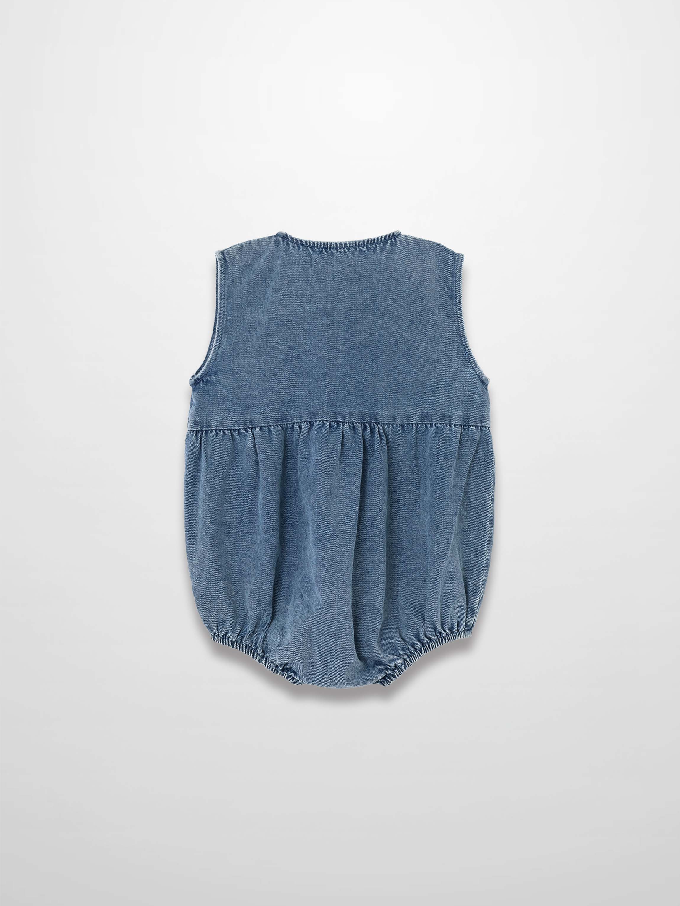Back view of blue denim romper with sleeveless design, gathered waist, and elastic leg openings.
