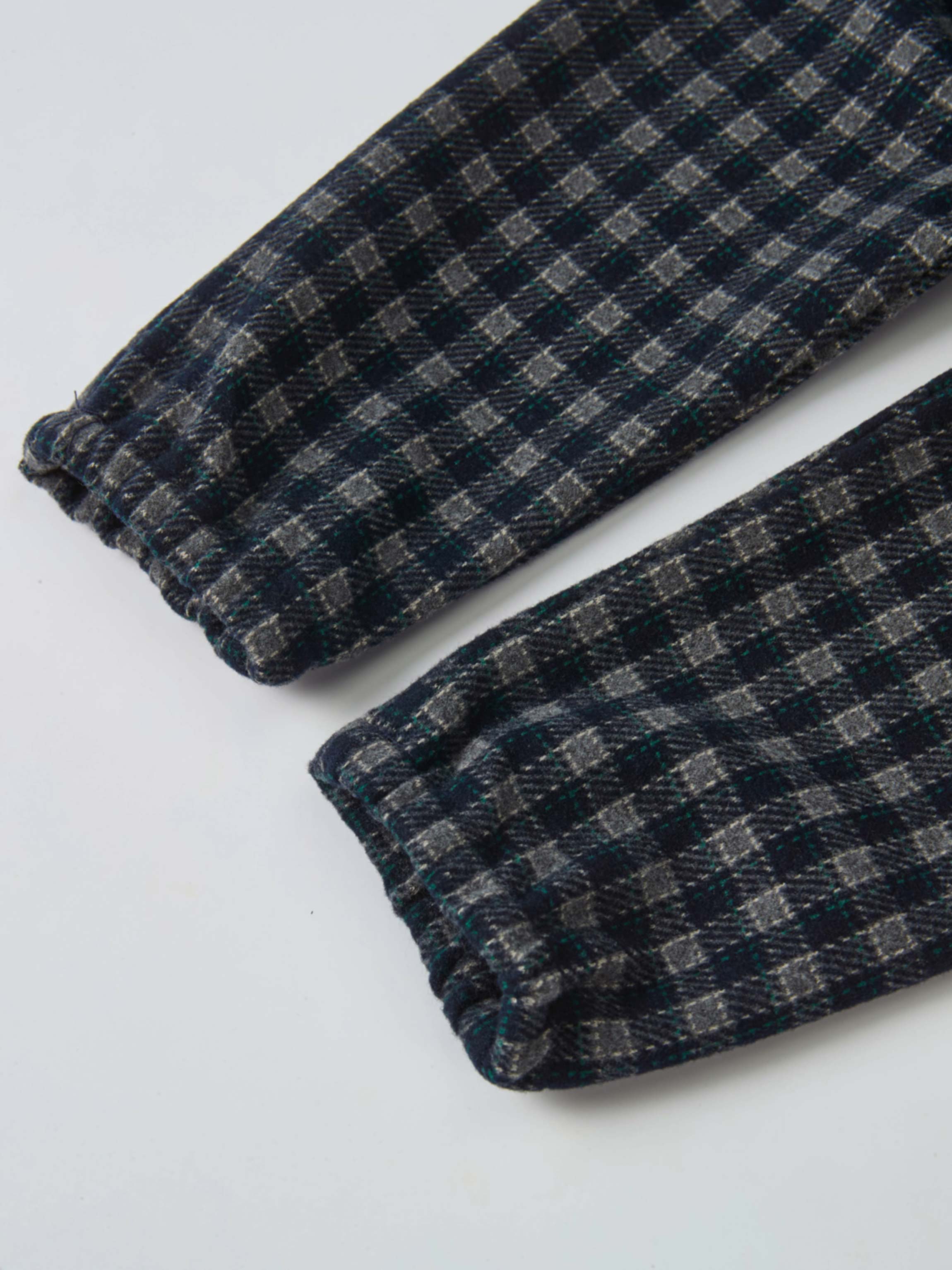 Girls plaid overalls fabric close-up in navy with grey and green checks, cuffed hems