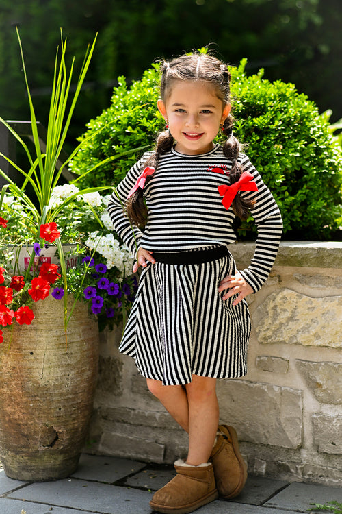 Girl wearing Striped Skirt - Black &amp; White: vertical stripes, ribbed fabric, flared circle silhouette, wide black elastic waist.