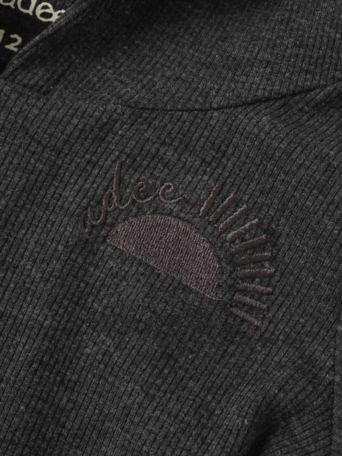 Grey ribbed hoodie set fabric close-up with embroidered rising sun and Adee logo.