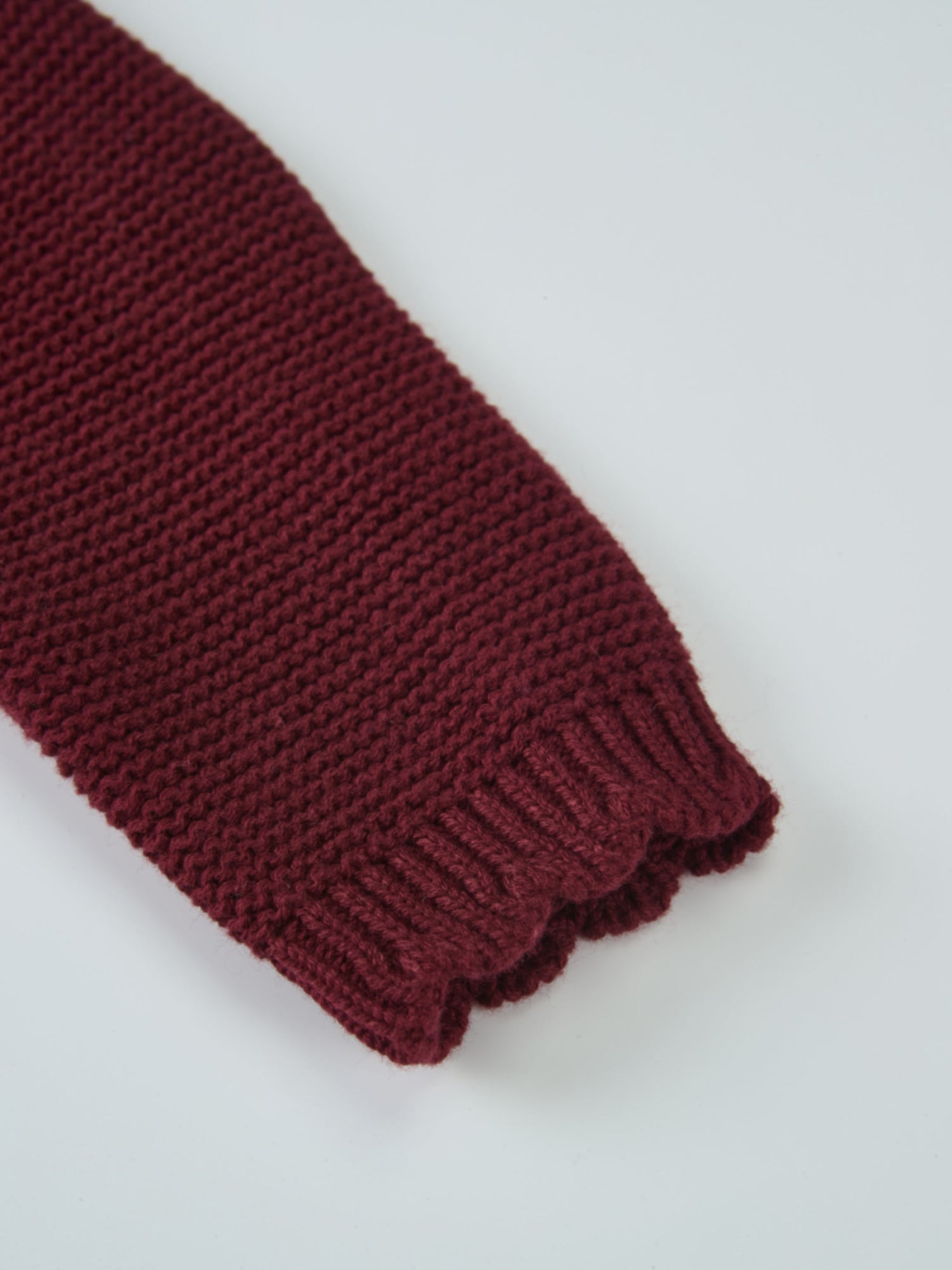 Cropped cardigan in burgundy knit with a ribbed cuff detail.