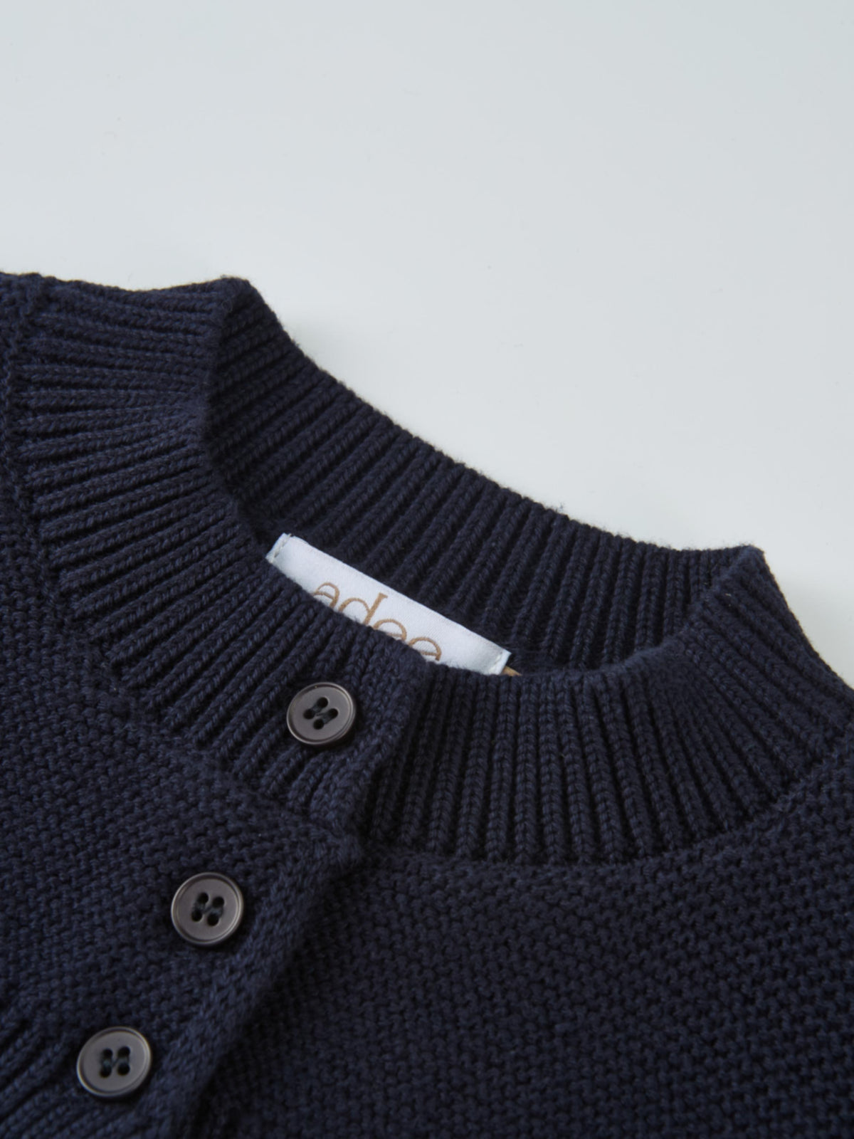 Cropped cardigan in navy by Adee, dressy unisex knit with button-front detail.