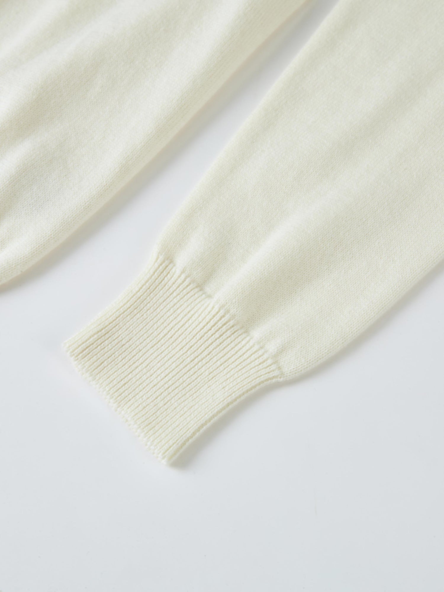 Ruffle Collar Knit Sweater by Adee in cream, close-up view of sleeve with ribbed cuff
