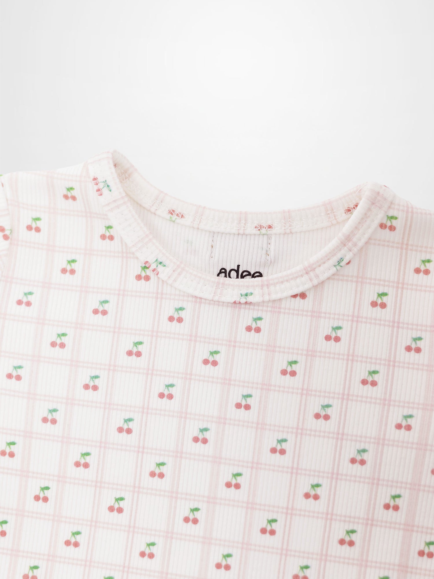 Girls Cherry Window Pajamas by Adee, light pink plaid grid with tiny red cherries and green stems throughout.