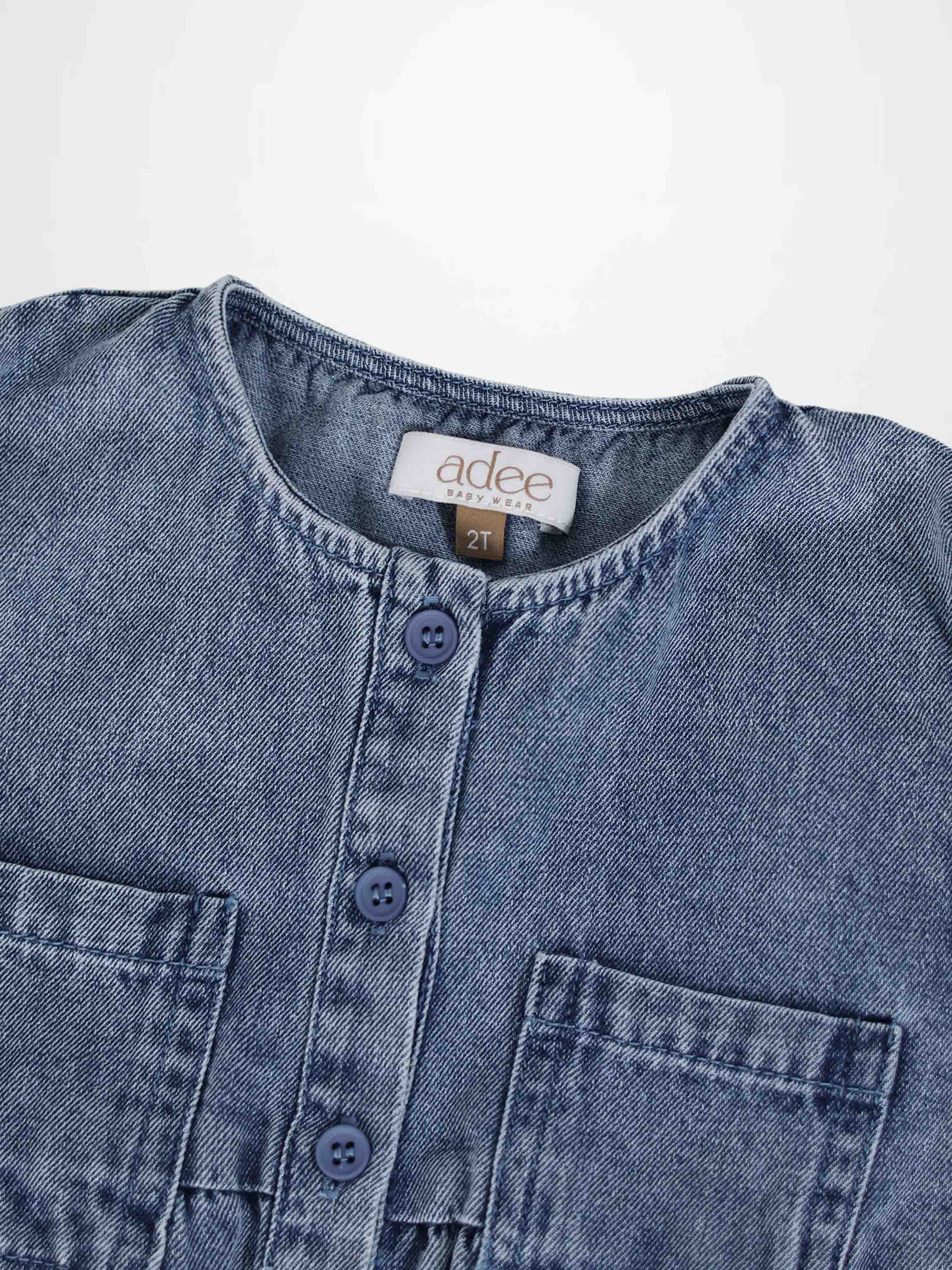 Blue denim romper with button-front placket and chest pockets, close-up.