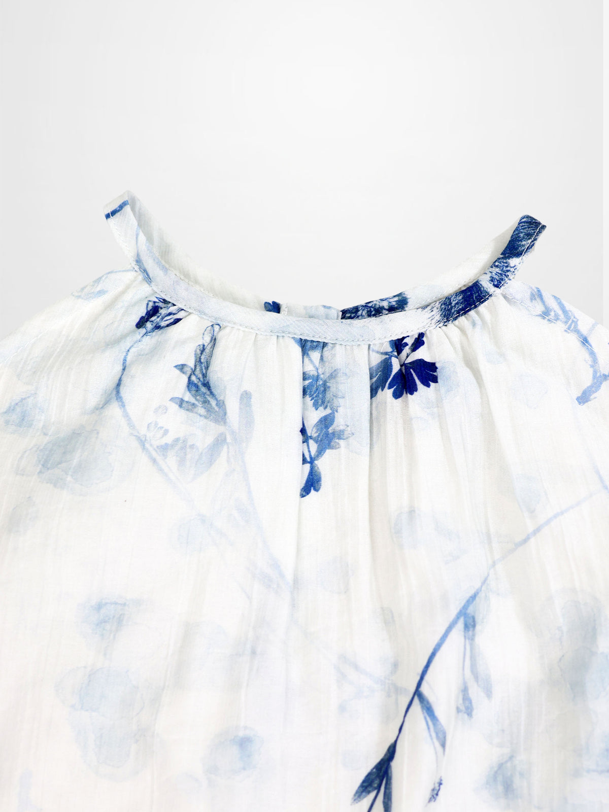 Blue Flower Jumper dress by Adee for girls; airy white fabric with blue floral print and a gathered neckline.