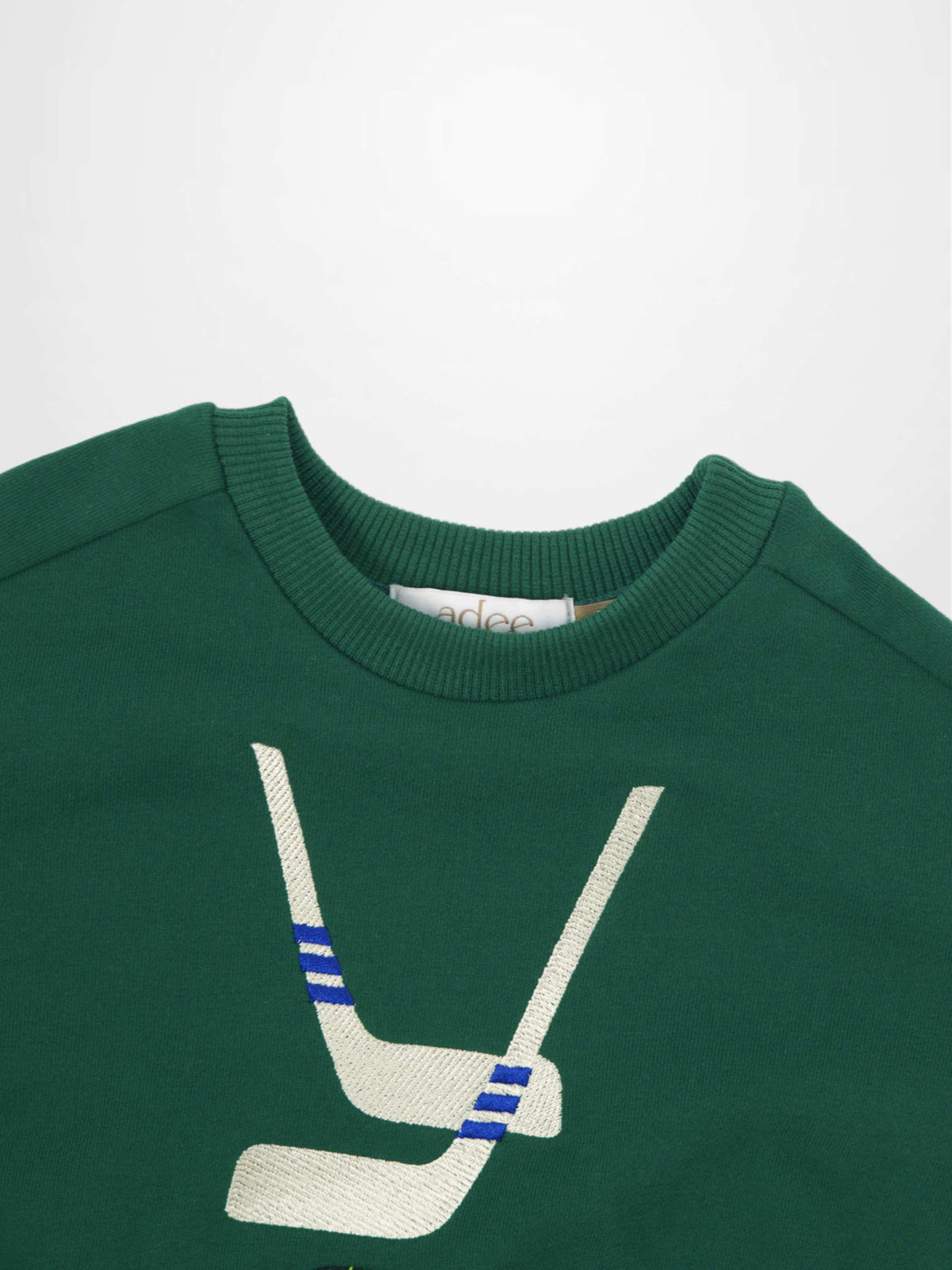 Hockey Sweatshirt for boys: dark green with white embroidered crossed sticks, blue stripes, and a black puck accent.