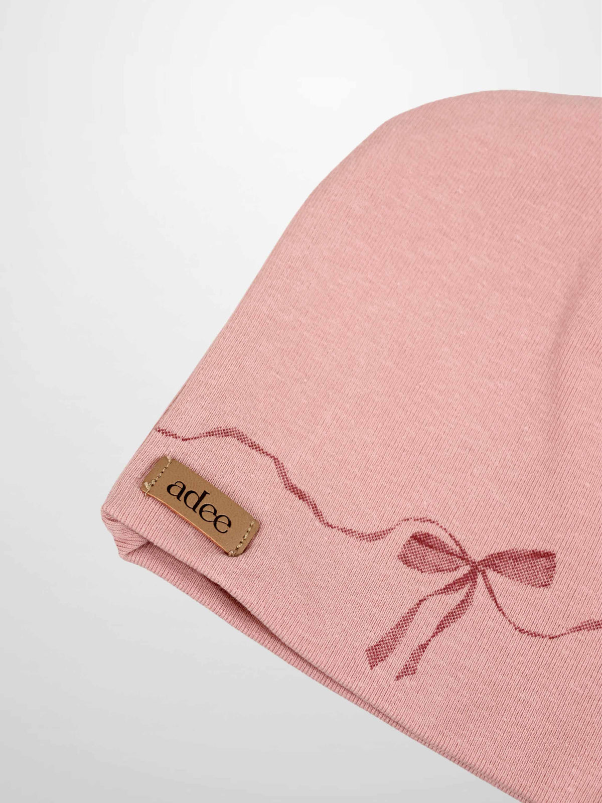 Pink bow beanie for girls by Adee with dark-pink wavy ribbon design and brand tag.