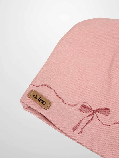 Pink bow beanie for girls by Adee with dark-pink wavy ribbon design and brand tag.