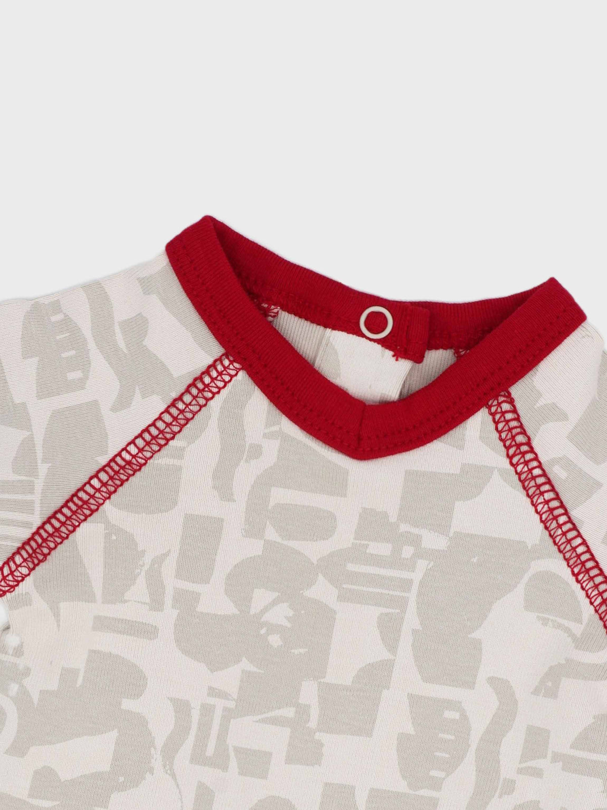 Red-trimmed neckline on abstract-print baby jumpsuit footie with soft neutrals.