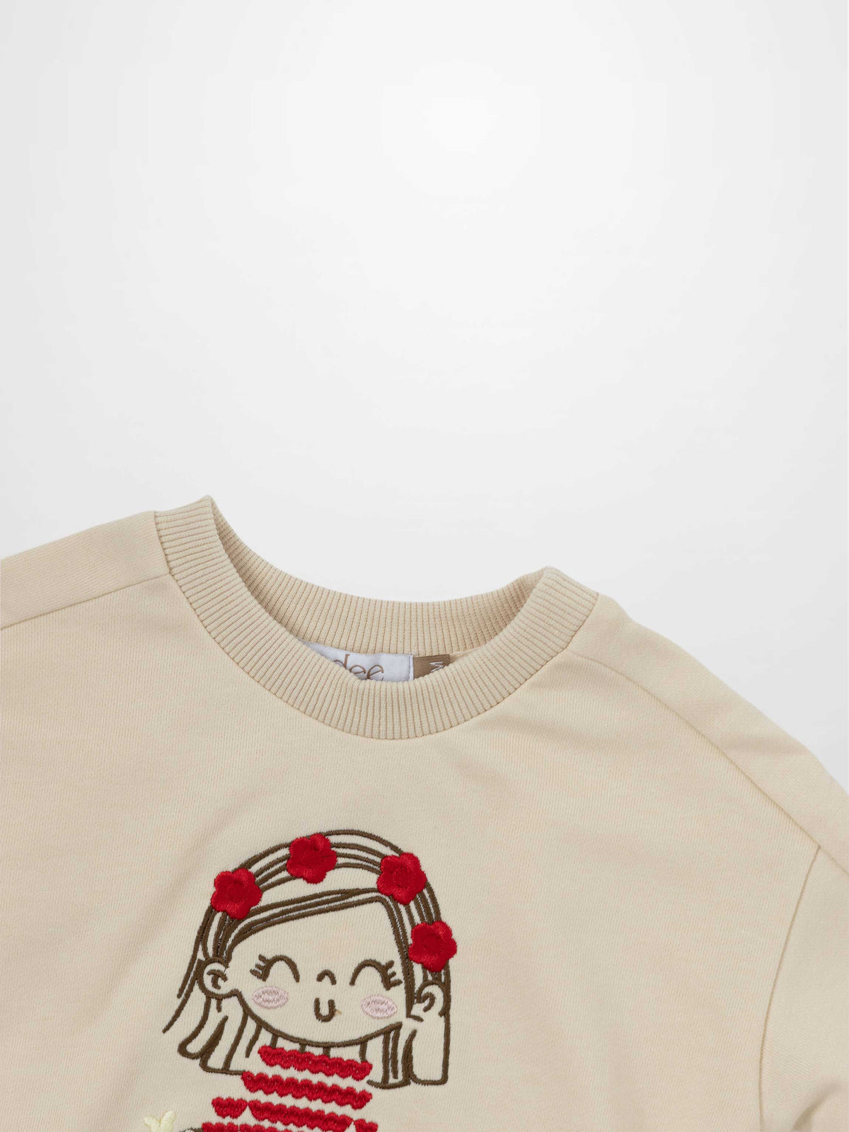 Embroidered Girl Sweatshirt by Adee, beige knit top with a smiling cartoon girl and red flower crown.