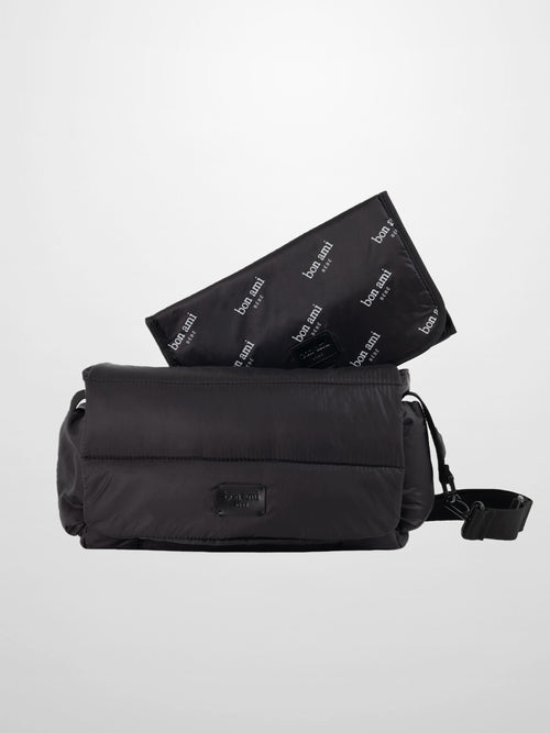 Black padded diaper bag with a foldover design and adjustable strap, a sleek, practical carry solution.