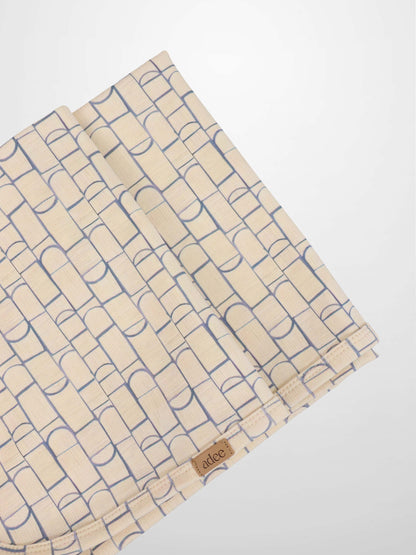 Geometric blanket swaddle by Adee, light blue rounded-rectangle pattern on beige fabric.