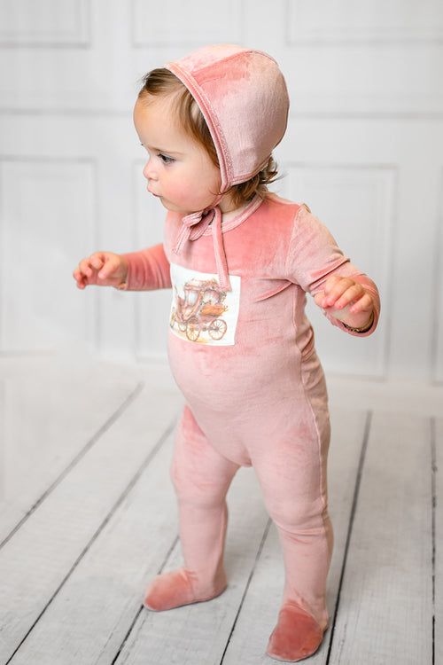 Velour Carriage Stretchy - Pink: baby girl in pink velour footed romper with vintage carriage patch, hooded with a bow.