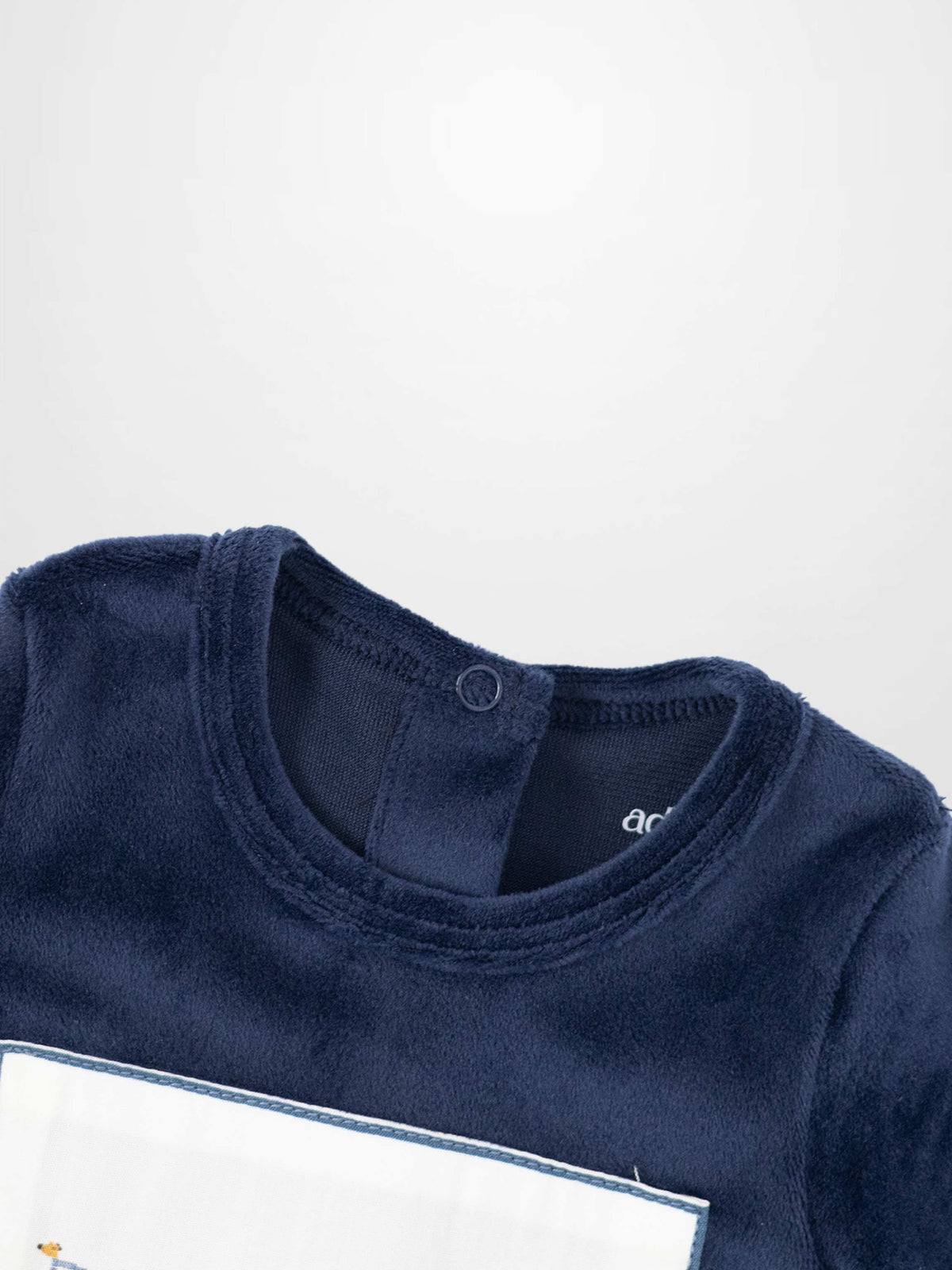 Navy plush velour baby footie with an embroidered center panel featuring a cheerful animal band.