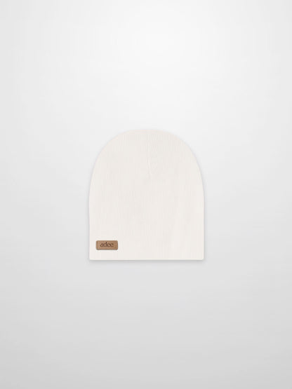 Thin ribbed white beanie by Adee; unisex baby/toddler knit hat with a small leather logo patch, ideal for cold days.