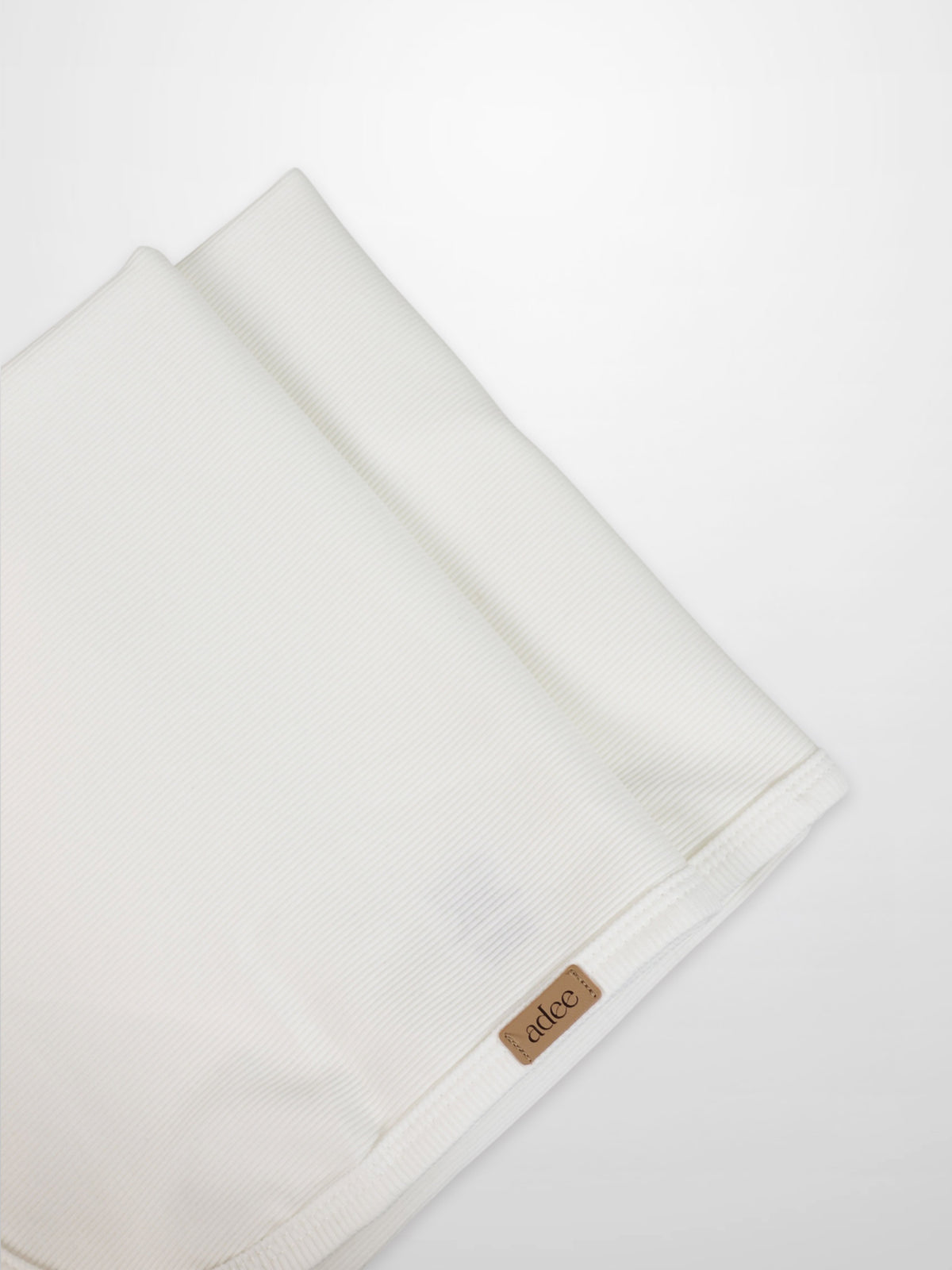 Thin ribbed white blanket by Adee for unisex, lightweight apparel and accessories, with visible brand tag at the edge.