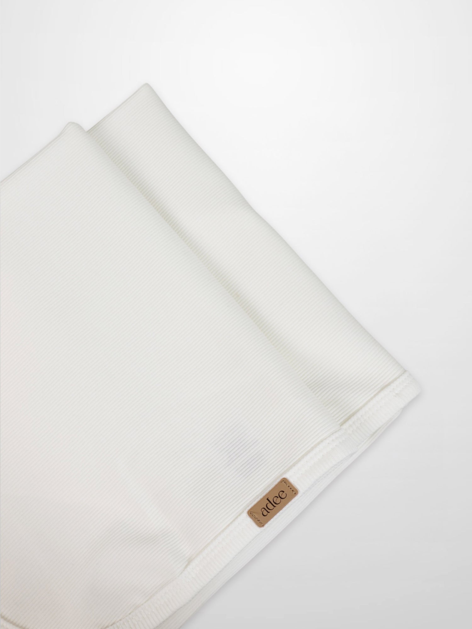 Thin ribbed white blanket by Adee for unisex, lightweight apparel and accessories, with visible brand tag at the edge.